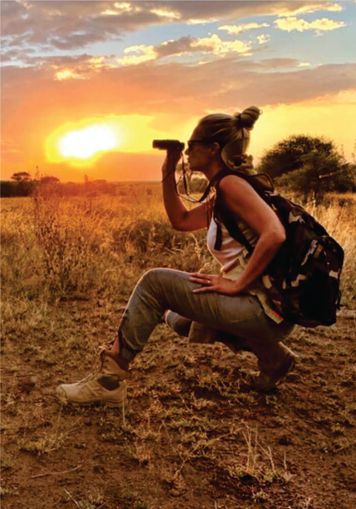 Woman looking through binoculars at sunset on affordable Kenya budget joining safaris for singles